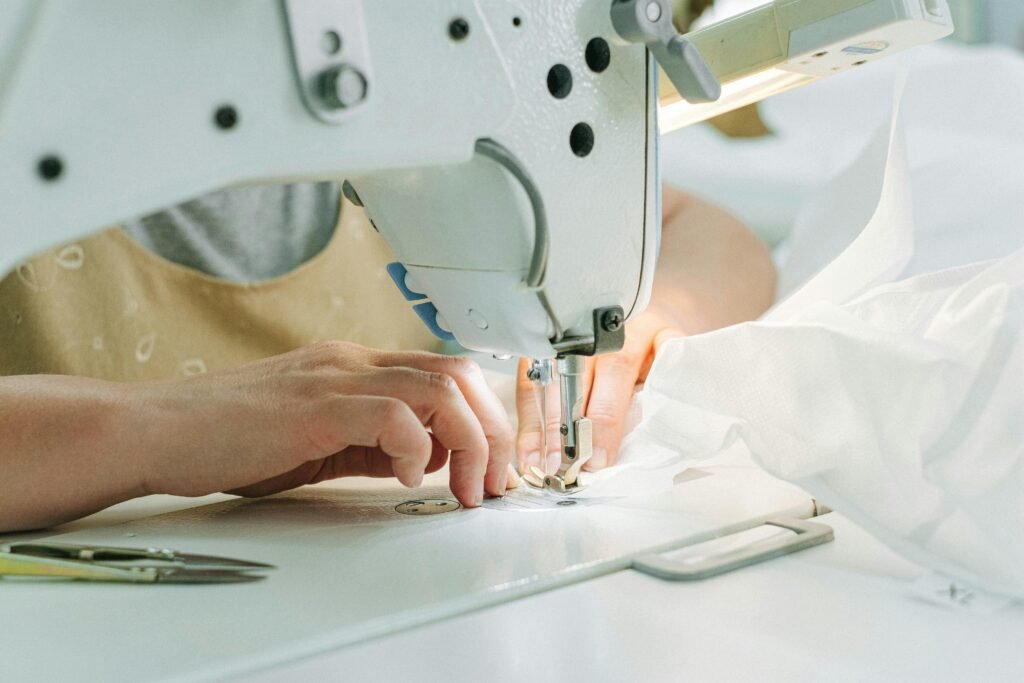 A seamstress using a sewing machine in a workshop, highlighting hands and fabric.