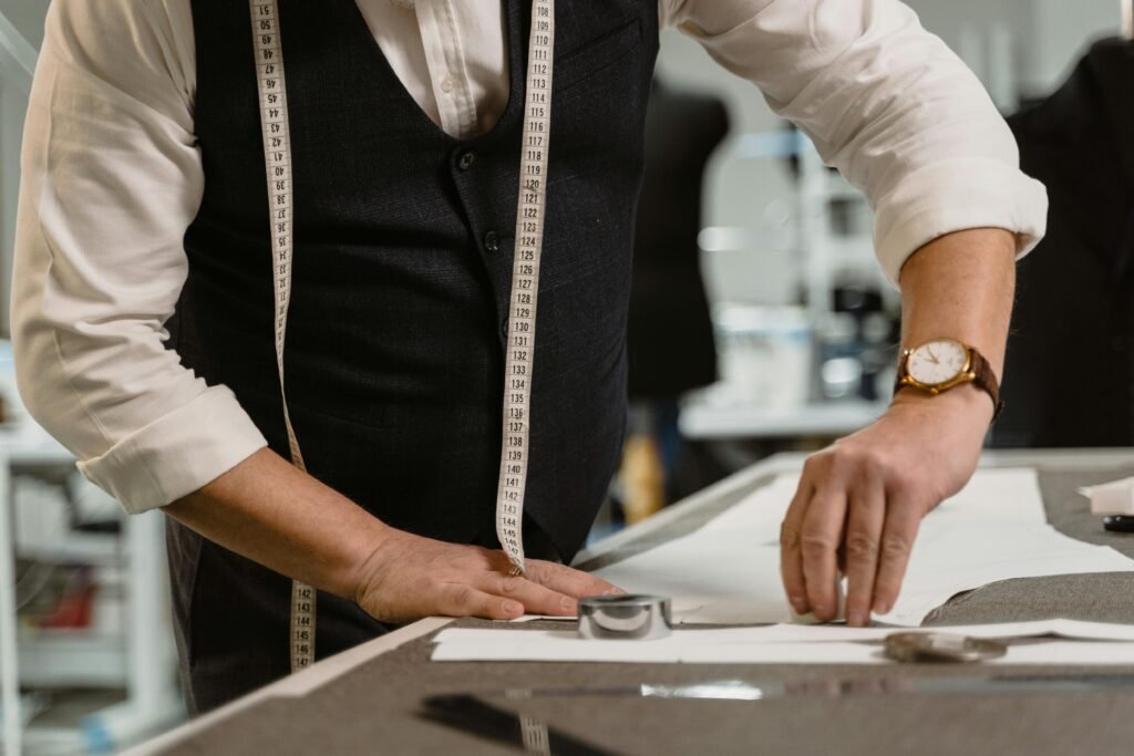 An experienced tailor measuring fabric on a workspace, showcasing precision and craftsmanship.